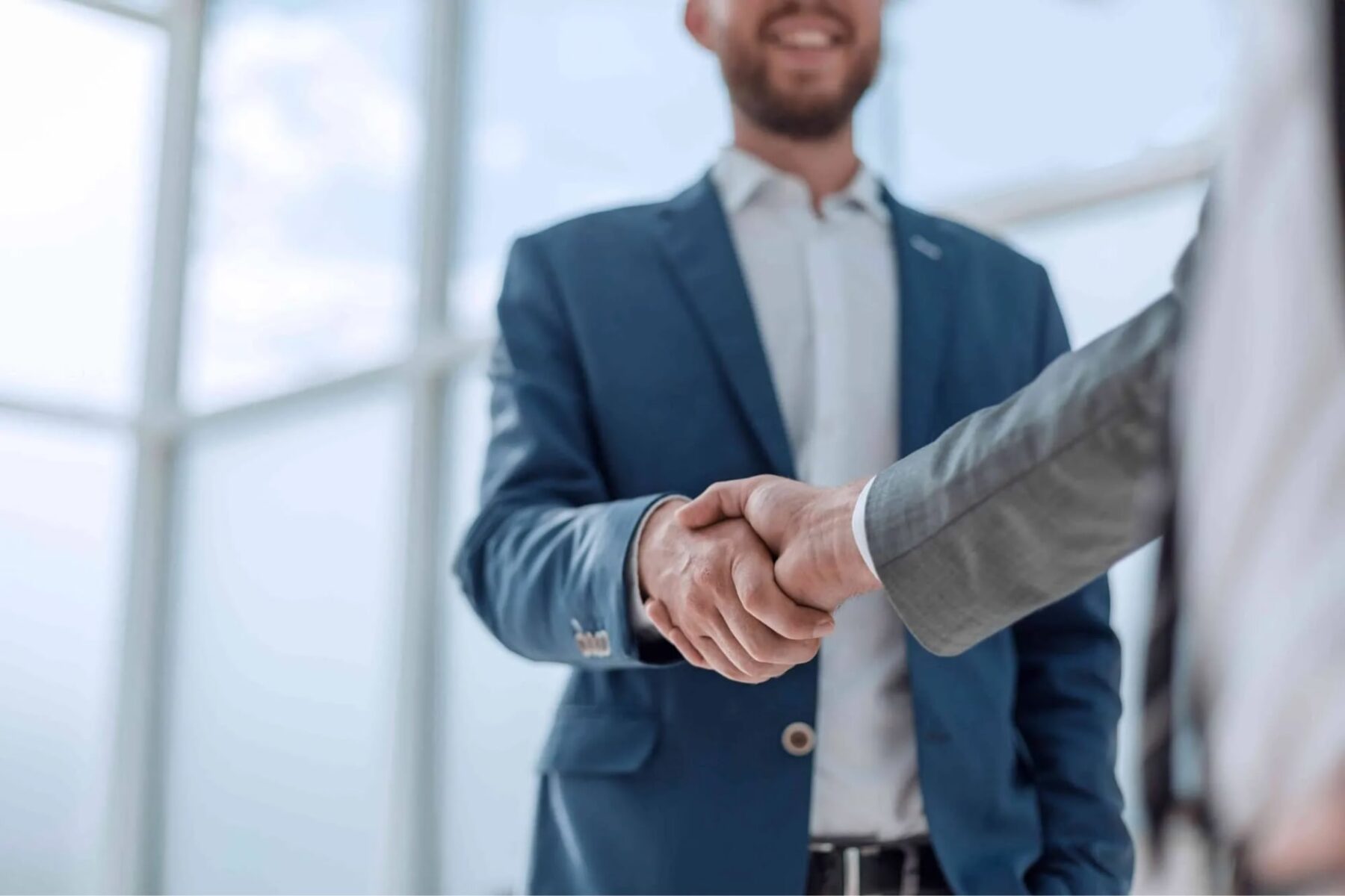 Two professionals shaking hands in business attire behind website banner text for a corporate talent referral program.